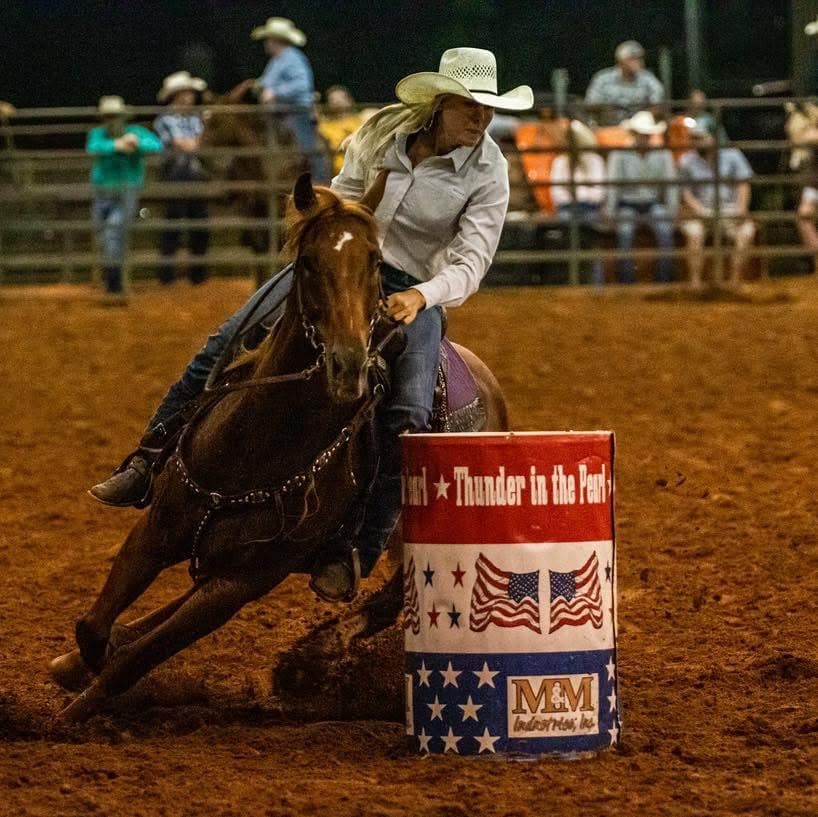 Jill barrel racing under the lights at a rodeo